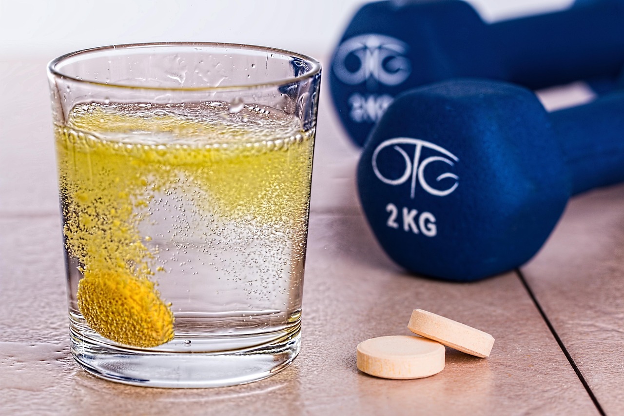 vaso-con-pastilla-de-vitaminas-efervescente-y-dos-mancuernas